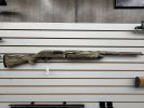 A camouflage-patterned rifle displayed on a wall rack.