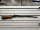 A wooden rifle displayed on a slat wall.