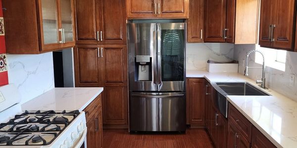 Modern kitchen with wooden cabinets and stainless steel refrigerator.