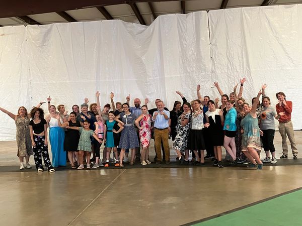 Group of people posing happily indoors with raised hands.