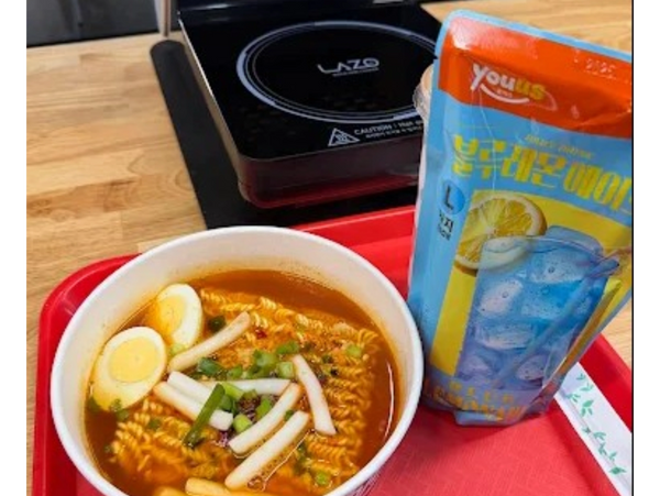 A bowl of spicy ramen with egg and rice cakes, paired with a lemon-flavored drink pouch.