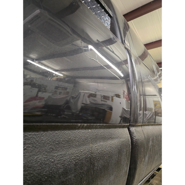 Close-up of a black vehicle's side panel showing smooth and textured surfaces.