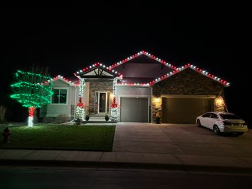 House decorated with red and white Christmas lights at night.