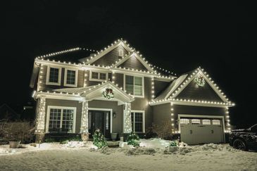 A house decorated with white Christmas lights on a snowy night.