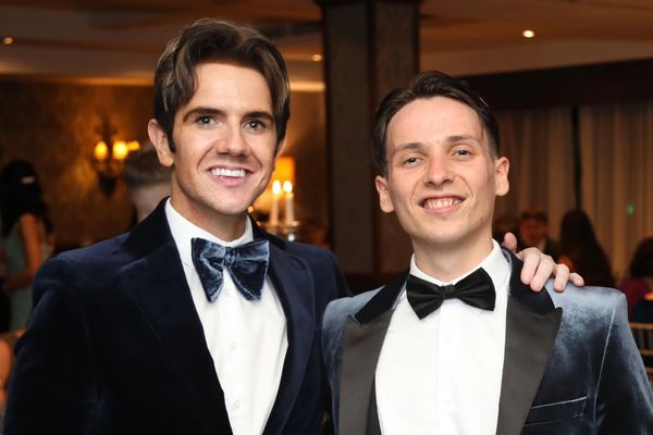 Two men in velvet tuxedos smiling at a formal event.