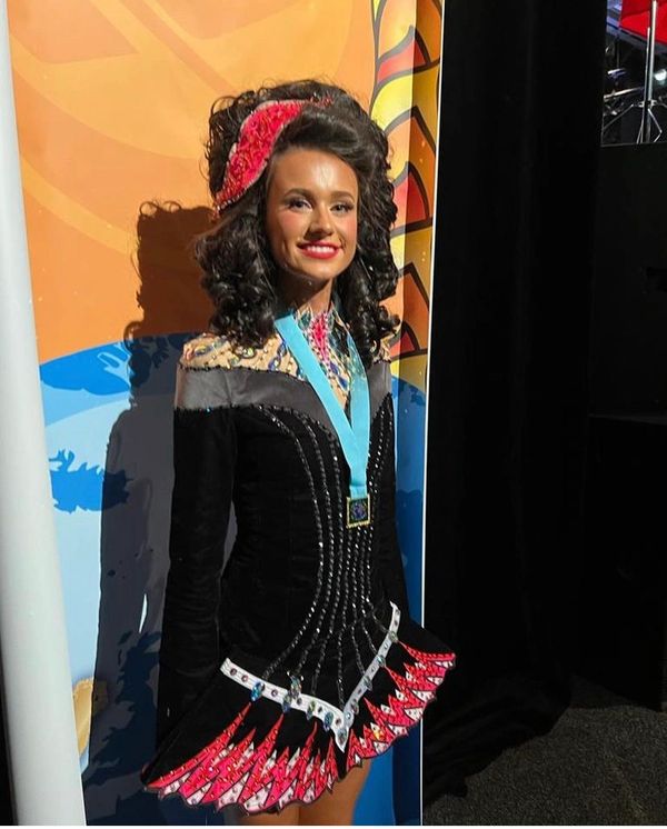 Young woman in a colorful Irish dance dress with a medal.