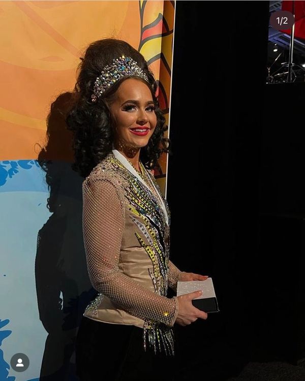 Woman in glamorous dress and jeweled headpiece smiling.