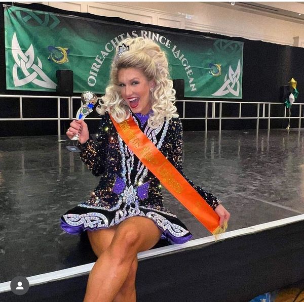 Winner with a trophy and sash at an Irish dance competition.