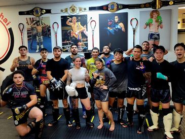 Group of Muay Thai fighters posing together in a gym.