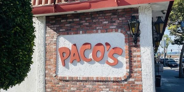 Signboard of a place named Paco's on a brick wall.