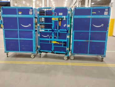 Three blue Amazon delivery carts in a warehouse setting.