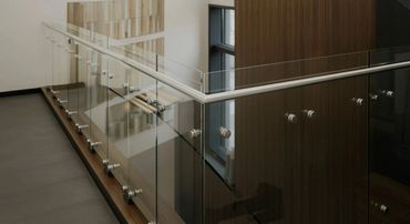 Modern glass railing with wooden accents in an interior space.