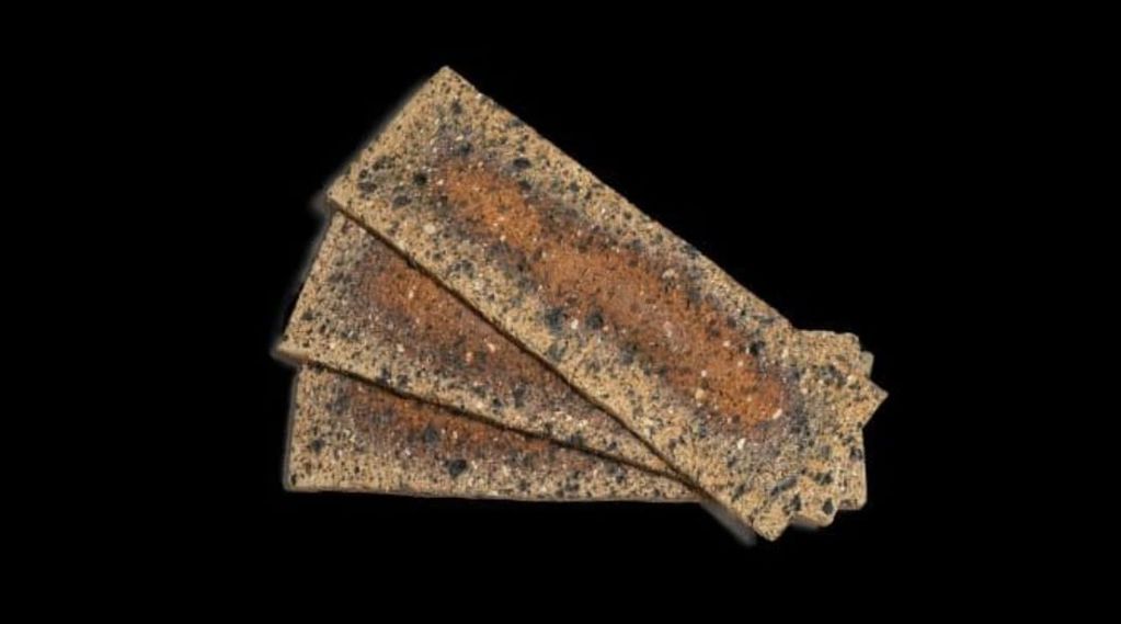 Three rectangular crispbread crackers with seeds on a black background.