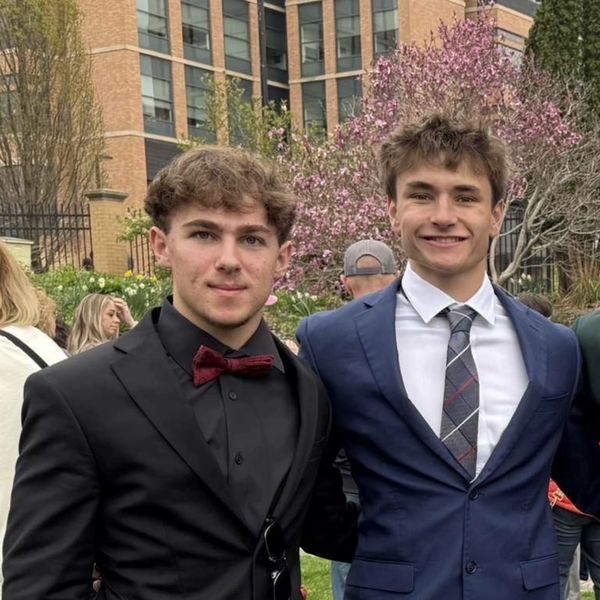 Two young men in suits posing outdoors.