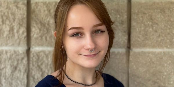 Young woman with septum piercing smiling gently at the camera.