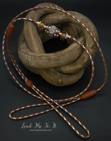 Intricately braided dog show lead with decorative beads and leather accents.