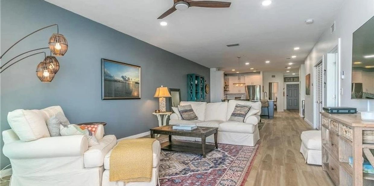 Bright living room with white sofas, wooden floors, and blue accent wall.