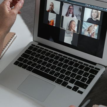 Person participating in a video conference on a laptop with six people.