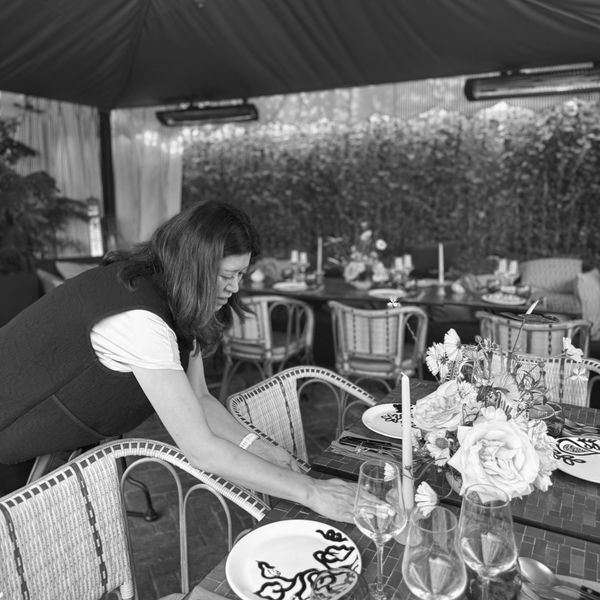 Woman arranging table settings in a decorated room.