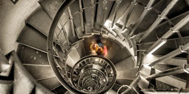 Spiral staircase viewed from above with blurred person descending.