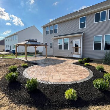 Paver patio with landscape surrounding, pergola, putting green, circular area for seating