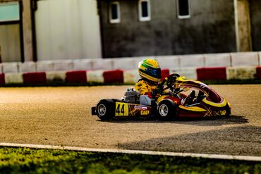 Young racer driving a go-kart on a track during sunset.