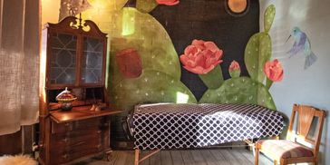 Cozy room with cactus mural, massage table, and antique furniture.