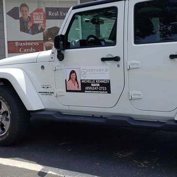 White Jeep with Century 21 real estate agent advertisement on door.