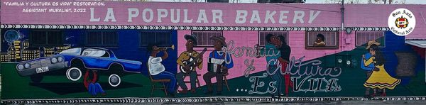 Colorful mural on La Popular Bakery depicting music, dance, and community life.