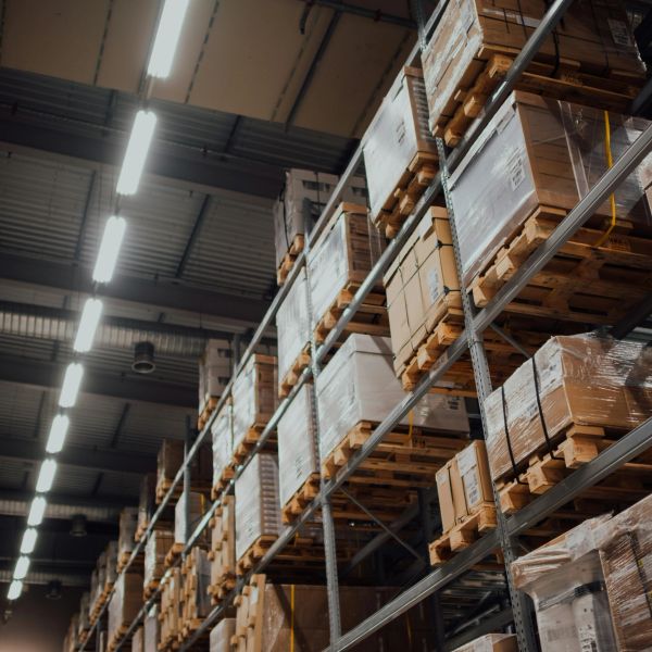 Tall warehouse shelves stacked with pallets of boxed goods under bright lights.
