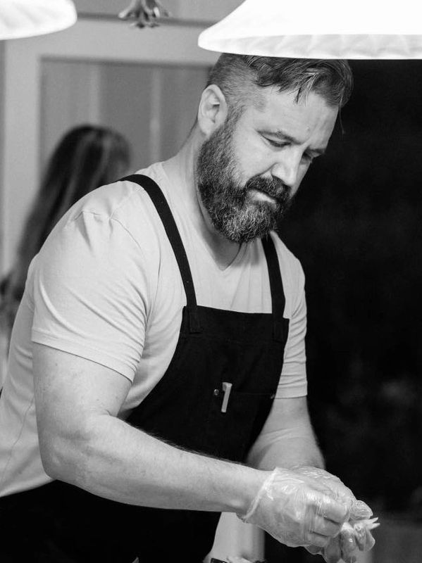 Bearded man wearing an apron and gloves working.