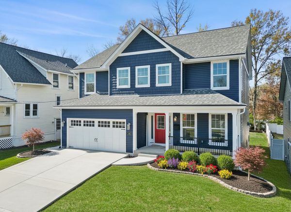 A modern blue two-story house with a red door and manicured front lawn.