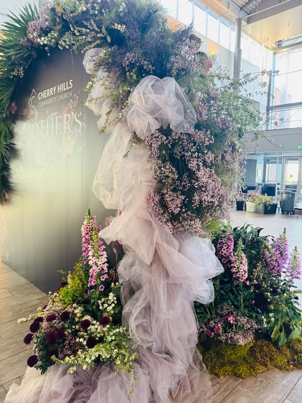 Elegant floral arrangement with cascading purple fabric in a modern indoor setting.