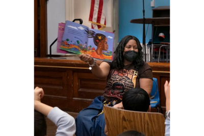 Dr. Sandra Holcomb, currently the chairperson of the TTLM Education committee, reads a book called B