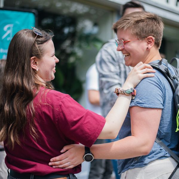 Zwei Menschen begrüßen sich vor einer Freikirche
