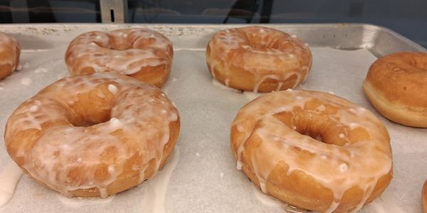 Glazed donuts on a baking tray.