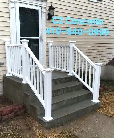 Newly constructed concrete stairs with white railings at a house entrance.