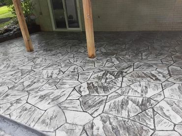 Stamped concrete patio with a stone pattern and wooden posts.