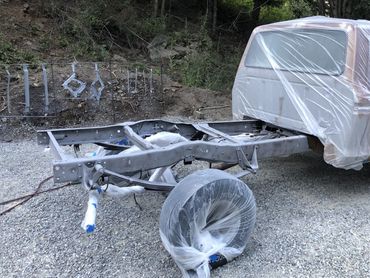 Partially disassembled truck with plastic coverings on parts, outdoors.