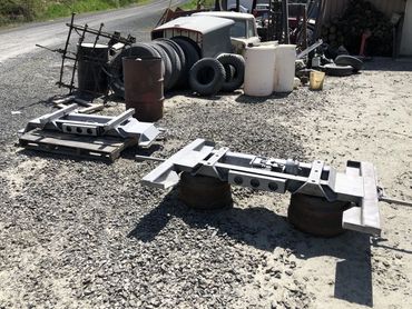 Industrial metal parts and tires arranged outdoors on gravel.