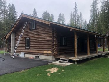 Rustic log cabin with ladders against the wall in a forested area.