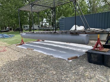 Metal structure with pontoon floats elevated on stands outdoors.