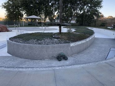 Empty, drained pool with a central concrete planter and small green toy truck.