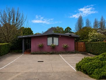 Small purple house with a concrete driveway and clear blue sky.