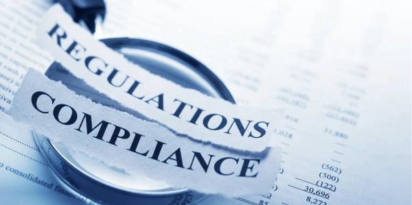 Magnifying glass highlighting compliance and regulations on financial documents.