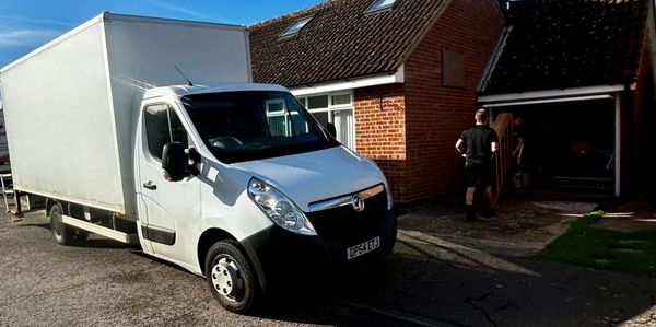 White delivery truck parked outside a brick house on a sunny day.