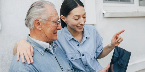 Caretaker teaching an elderly how to use laptop