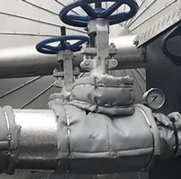 Insulated industrial pipes with valves and a pressure gauge.