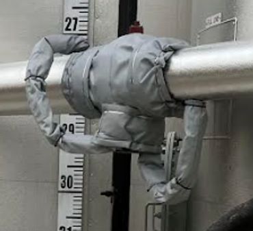 A metallic pipe with a wrapped insulation cover in an industrial setting.
