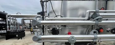 Industrial facility with metal pipes and tanks under an overcast sky.